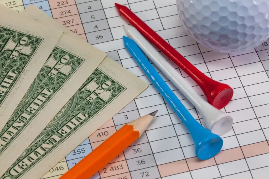 Us dollar banknotes and golf equipments lying  on a golf score card